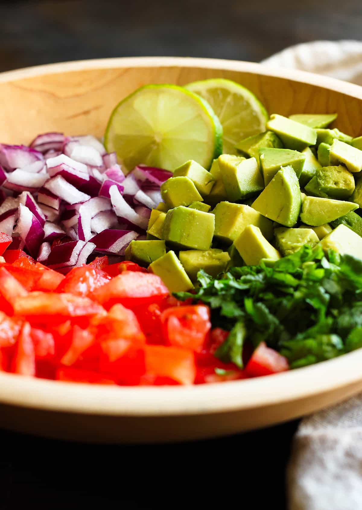 Tomato avocado salad in a bowl with lime, cilantro, and red onion