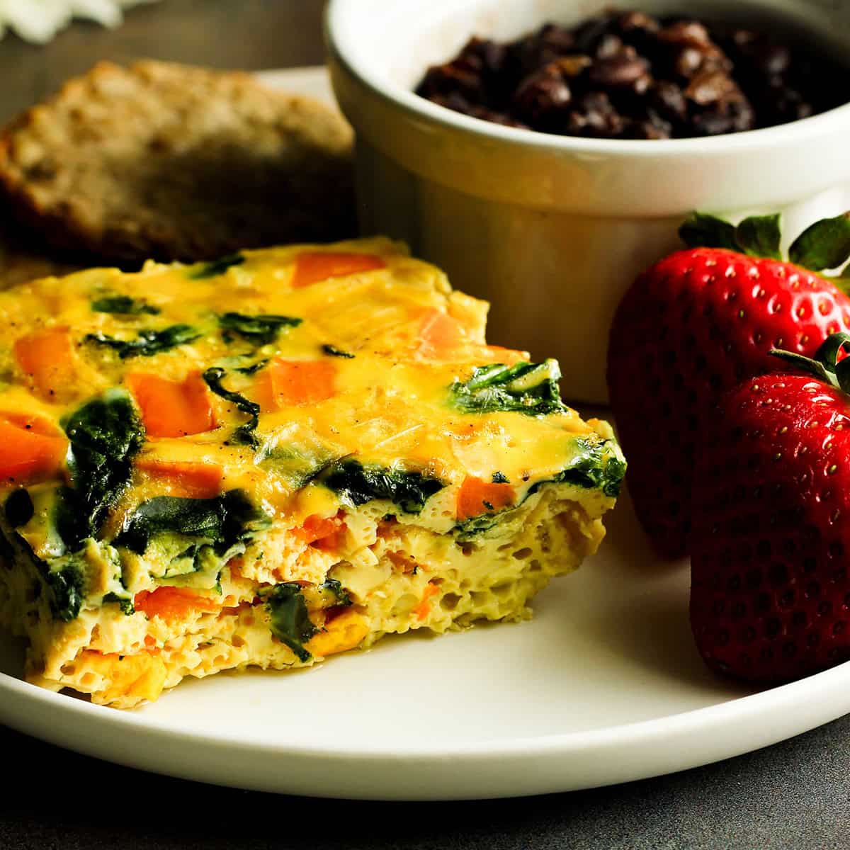 baked eggs with egg whites served with a side of chicken sausage, beans, and strawberries